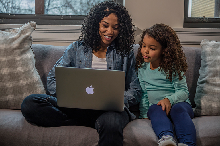 Woman sitting with daughter looking at computer