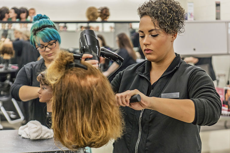 Cosmetology students practicing on manikans.