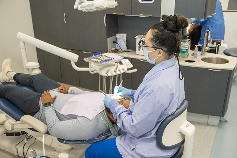 student examining and cleaning a patient's teeth