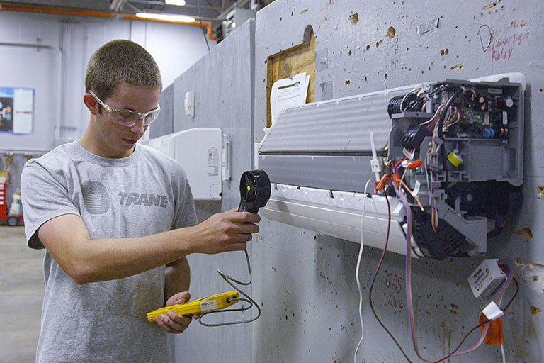 Student using a tool to scan an incomplete air conditioning unit