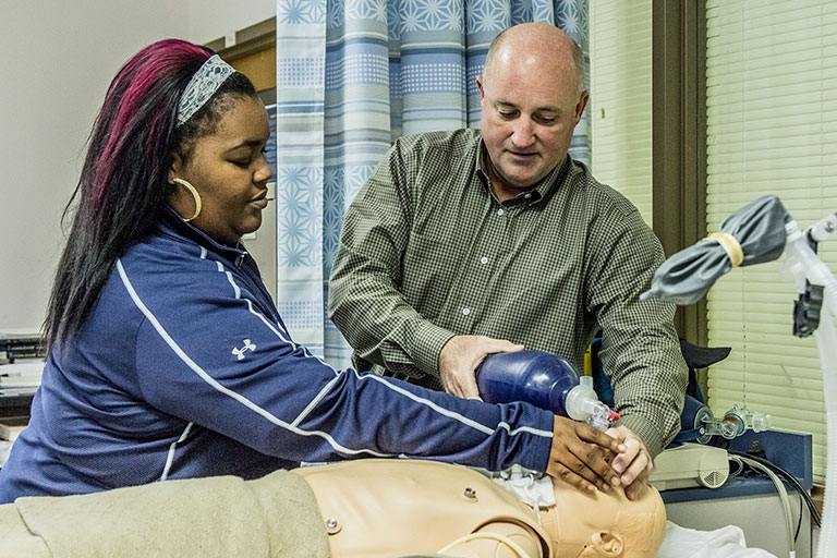 student and instructor with a breathing device on a mannequin
