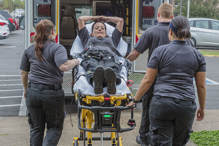 Woman being carried onto an ambulance in a stretcher