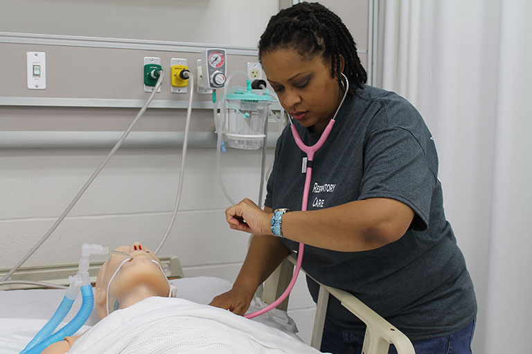 student listening to patients lungs